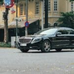 Czarny luksusowy sedan jedzie ulicą miasta wśród zabytkowych kamienic