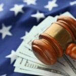 Młotek sędziowski na dolarach na tle flagi USA